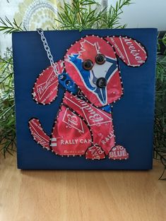 a blue box with a red and white dog made out of soda cans on it