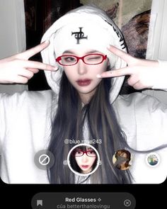 a girl wearing glasses and a white hoodie is holding her hands up in front of her face