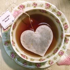 a cup of tea with a heart shaped tea bag in it and a note attached to the top