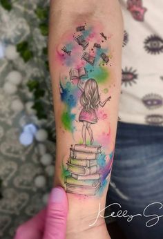 a person with a tattoo on their arm holding a stack of books in the air