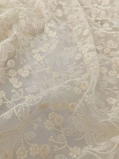 white lace with flowers and leaves is shown in close up on a tablecloth background