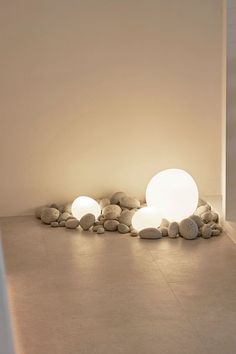 two lamps sitting next to each other on top of a stone covered floor in front of a white wall