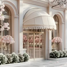 the entrance to a luxury building with pink flowers in front and white columns on either side