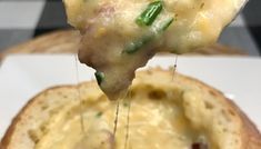 a close up of a piece of food on a fork with cheese and green peppers