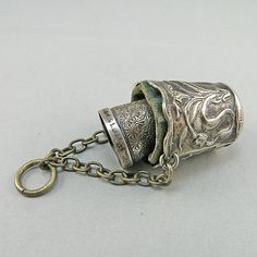 an old metal cup with chains hanging from it's sides on a white surface