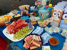 a blue table topped with lots of food and desserts covered in cartoon character pictures