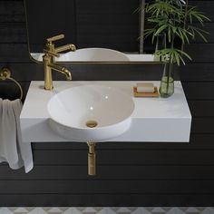 a white sink sitting on top of a counter next to a green potted plant