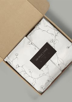 an open box with a white and black floral print on it, sitting next to a brown cardboard package