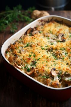 a casserole dish with mushrooms and parmesan cheese in it on a wooden table