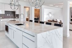 a large kitchen with marble counter tops and white cabinets in the center, along with an island