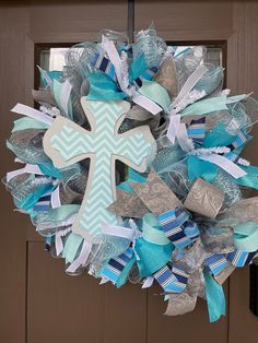 a blue and white wreath with a cross on the front door, decorated with ribbons