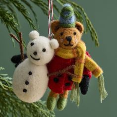 two stuffed animals hanging from a christmas ornament on a pine tree with needles