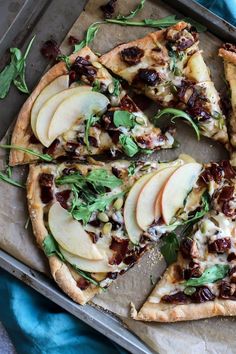 an apple and walnut pizza is shown on a baking sheet with fresh herbs, sliced into slices