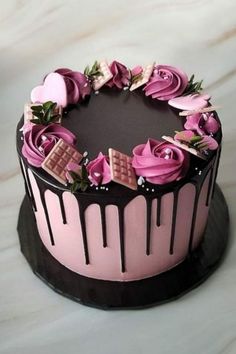 a chocolate cake decorated with pink roses and chocolate bars