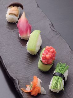 sushi is arranged on a slate platter ready to be eaten