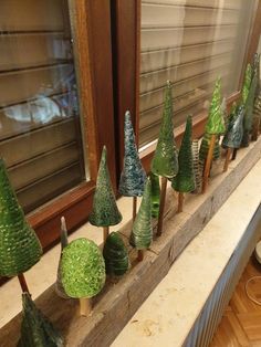 small green trees sitting on top of a wooden shelf in front of a store window