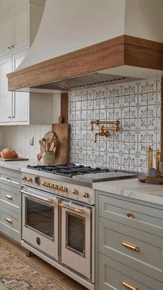 an image of a kitchen setting with white cabinets and gold pulls on the oven hood