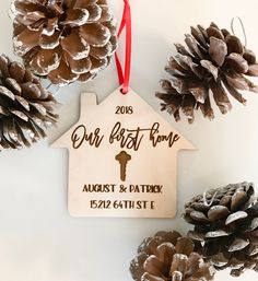 some pine cones are next to a house ornament with the words our first home on it