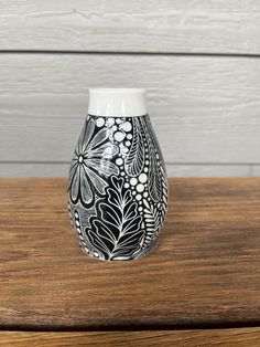 a black and white vase sitting on top of a wooden table