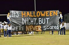 a group of cheerleaders hold up a banner that reads it's halloween night, but we're never scared