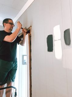 a man is painting the walls in his house with green and white paint on it