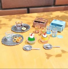 a table topped with plates and cups filled with desserts next to a box on top of a wooden table