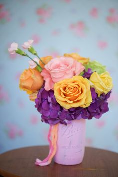 a vase filled with lots of different colored flowers