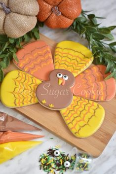 a decorated turkey cookie sitting on top of a wooden cutting board next to other decorations