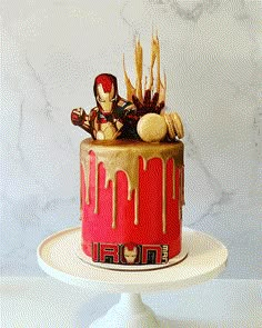 the cake is decorated with iron man figures and drizzled gold icing