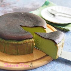 a chocolate and green cake on a wooden plate with a slice missing from the cake