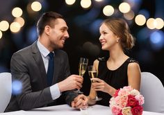 a man and woman sitting at a table with champagne glasses in their hands, looking into each other's eyes