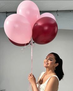 a woman is holding some pink and red balloons