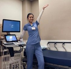 a woman in scrubs standing next to a hospital bed with a laptop on it