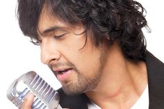 a man with curly hair holding a microphone in his right hand and singing into it