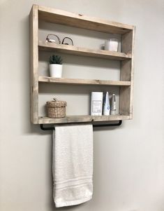 a bathroom shelf with two shelves above it and towels hanging on the wall next to it