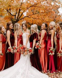 a group of women standing next to each other in long red dresses and holding bouquets