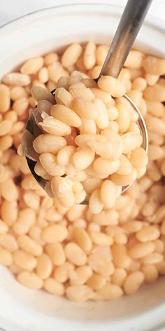 a spoon full of beans in a white bowl