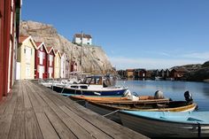 several boats are docked in the water next to some red and yellow buildings on a wooden pier