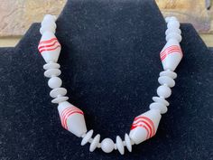 "This beautiful signed Japan necklace features art glass red and white oblong beads separated by smaller milk white beads. Shepherd's hook closure. Probably dates to the 1940s/50s but has an Art Deco design.  12\" choker length so very small size. The necklace can be adjusted to add another 2.5\" by placing the hook further along the beads. The Japan hallmark is on the hook (I needed a magnifying glass to see it).   In good vintage condition although the hook closure and other metalwork is discoloured. There is also a tiny mark on one of the separator beads.  Please note that all jewellery sold at Cheryl's Treasure Box is in vintage condition and I encourage you to look at the detailed photos. All stones/ metals are costume unless otherwise stated. Feel free to message me with any question Shepherds Hook, Le Crochet, Detailed Photos, Treasure Box, White Milk Glass, Beaded Choker Necklace, Magnifying Glass, Necklace Vintage, Art Deco Design