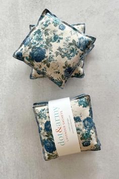 two blue and white pillows sitting next to each other on top of a gray surface