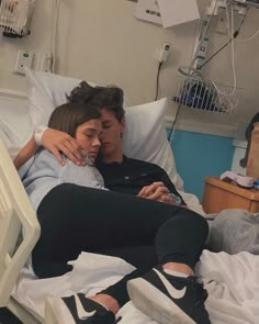 two people in a hospital bed one is hugging the other