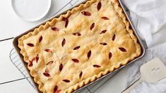 a pie sitting on top of a cooling rack next to a plate and spoons