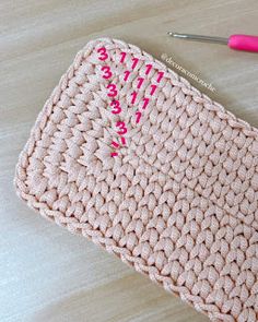 a crocheted pink purse sitting on top of a table next to a pair of scissors