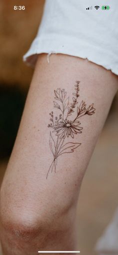 a woman's leg with a tattoo on it that has a plant growing out of it