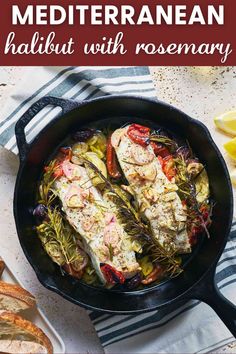 a pan filled with fish and vegetables on top of a table next to sliced bread