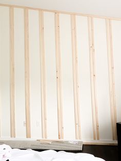 an unfinished room with white walls and wood slats on the wall, in front of a flat screen tv