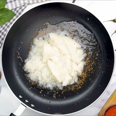 the food is being cooked in the pan on the stove top with some seasoning next to it