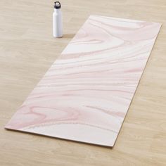 a pink and white marbled paper on a wooden floor next to a water bottle