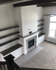 an empty living room with fireplace and shelves