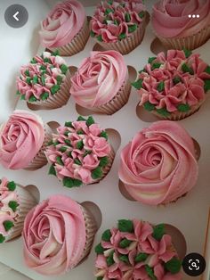 cupcakes decorated with pink frosting and green leaves on white tray next to each other